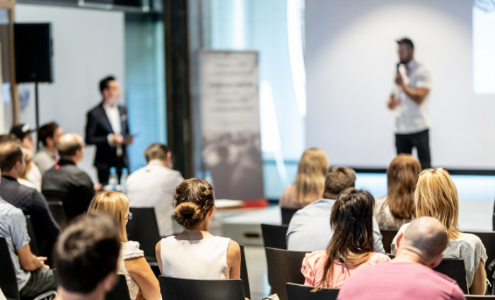 Entrepreneur enthusiastically presenting a pitch with a microphone to an audience