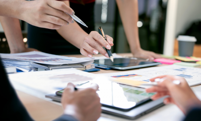 Image is a close up shot of business people's hands with tablets