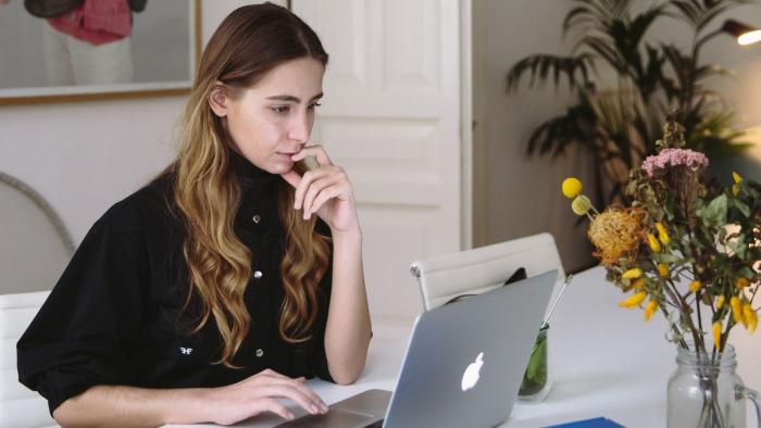 woman working on a laptop  with flowers on the desk