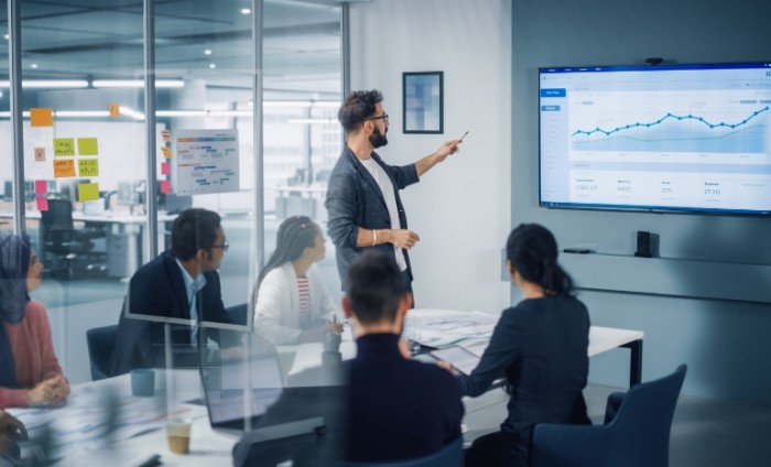 Image shows a man presenting during a meeting