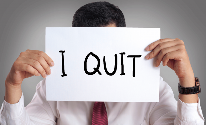 A man holding a sign saying "I QUIT".