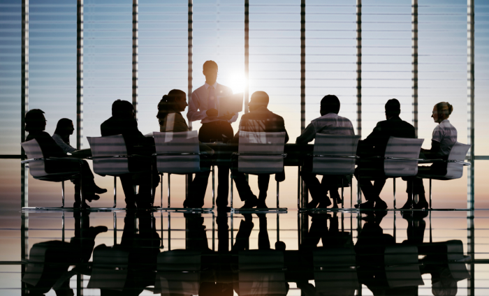 Image shows a group of people in a board meeting